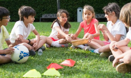 Children sat in a semi-circle on grass
